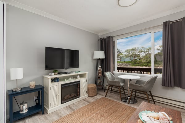 Relax in your inviting living space with cozy seating, a warm fireplace, and peaceful waterfront views framed by large windows that fill the room with natural light.