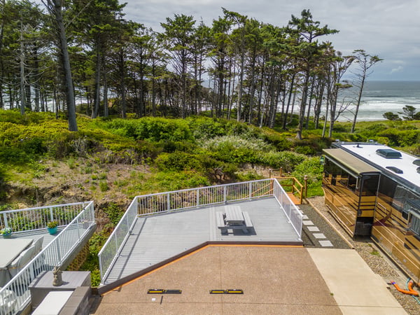 Coastal retreat featuring expansive deck space with natural beachfront access, surrounded by windswept pines and ocean breezes. Perfect for outdoor gatherings and soaking in the serene seaside setting.