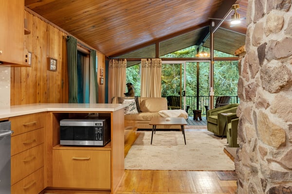 Settle into your cozy retreat where warm wood tones and peaceful forest views through expansive windows create your perfect mountain getaway.