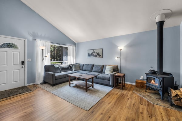 Picture yourself unwinding on the plush sectional while the crackling fire warms the room. Soft blue walls and natural light create your perfect mountain retreat.