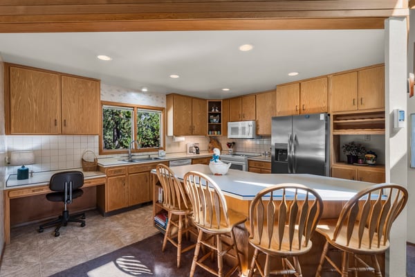 Cook together in this spacious kitchen featuring warm wood cabinets, modern appliances, and a sunny breakfast bar perfect for morning coffee.