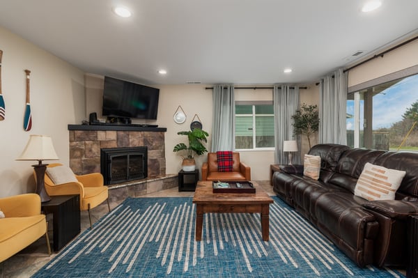 Sink into the leather sofa by your cozy stone fireplace, where the TV awaits your favorite shows and natural light streams through elegant curtains.