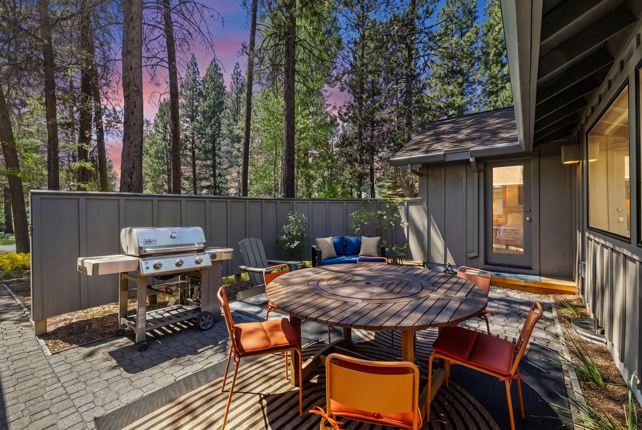 Picture yourself dining al fresco as the sky turns shades of pink and blue. Your private patio offers a gas grill for cooking, a spacious table for meals, and cozy seating surrounded by towering pines.