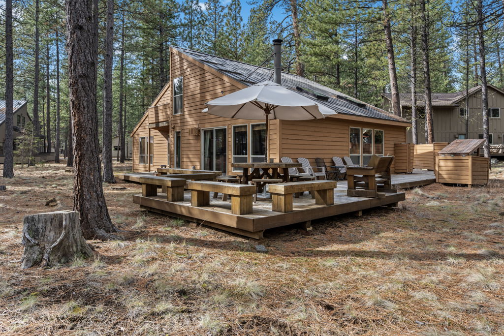 Mountain cabin with expansive deck, perfect for forest relaxation and outdoor dining among towering pines.