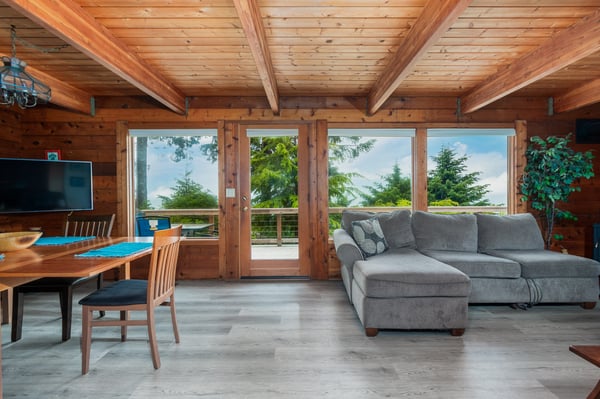 Your cozy living space features warm wood beams, plush seating, and stunning mountain views through glass doors opening to your private balcony—perfect for morning coffee or starlit evenings.