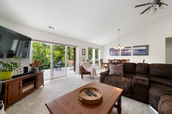 Sink into plush seating in your open-concept living area, where large glass doors frame views of lush greenery and lead to your private patio retreat.