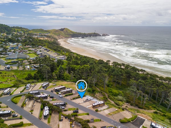 Coastal property nestled between forested hills and sandy beach, offering access to scenic oceanfront setting and nearby lighthouse landmark.