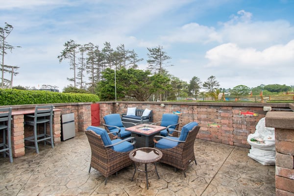 Relax with friends and family in your private outdoor retreat, where comfortable wicker seating and a cozy fire table create the perfect gathering spot under open skies.
