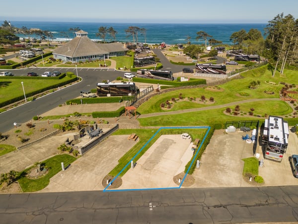 Coastal RV resort property offering spacious paved parking sites with ocean views, lush green landscaping, and direct beach access in a scenic seaside community.