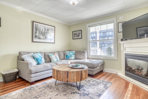 Unwind on your plush sectional sofa beside the warm fireplace, where thoughtful decor and city views create the perfect space for relaxation.