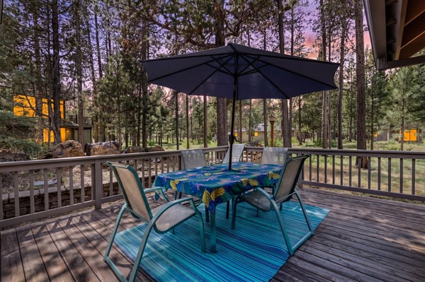 A peaceful forested setting where neighboring cabins glow warmly in the background as the sun sets through the pines.
