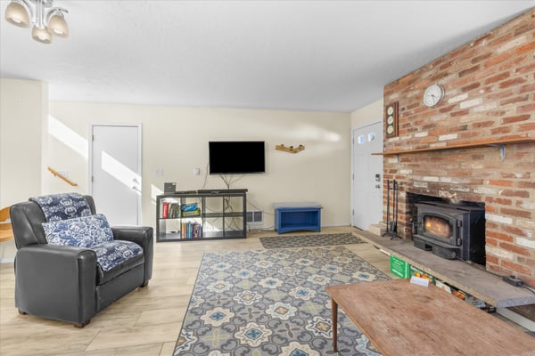 Cozy up in your inviting living room with exposed brick fireplace, comfortable seating, and entertainment center for relaxing evenings.