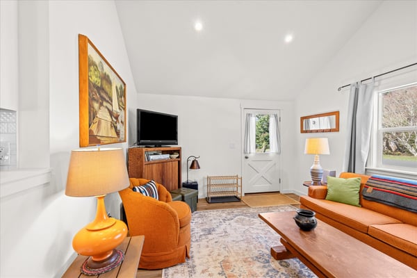 Sink into plush orange seating surrounded by warm wood accents and vintage charm in this inviting living space.