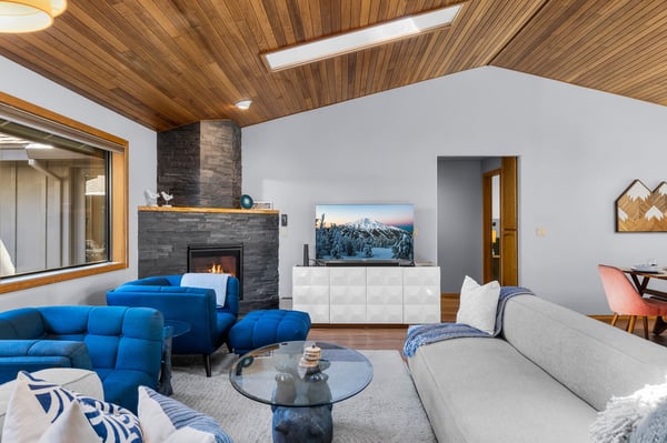 Gather around the warm fireplace in this inviting living space, where vaulted wood ceilings and mountain views create your perfect alpine retreat. The plush seating and modern design welcome you home after a day of adventure.