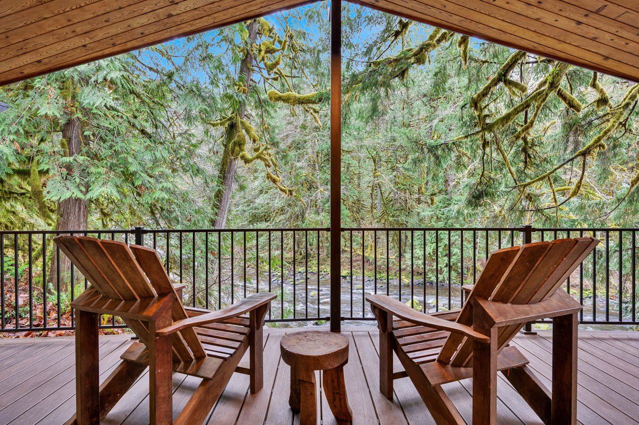 Relax in rustic Adirondack chairs on your private covered deck, surrounded by towering moss-draped trees and peaceful forest views that make every moment feel like an escape.