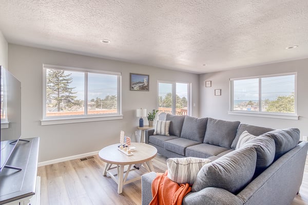 Sink into your plush sectional and take in scenic coastal views through three large windows. The bright, airy living room invites you to unwind with ocean breezes nearby.