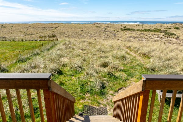 Coastal dunes and grasses stretch toward the ocean, creating a natural seaside landscape near the property.