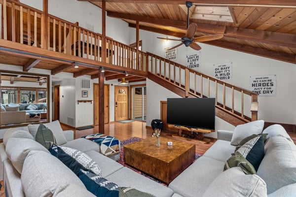 Sink into plush sofas beneath soaring wooden beams in your spacious living room, where rustic charm meets modern comfort perfectly.