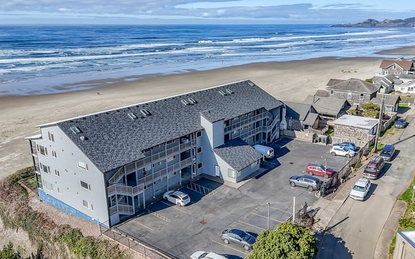 Oceanfront property situated directly on pristine sandy beach with rolling waves and coastal mountain backdrop.