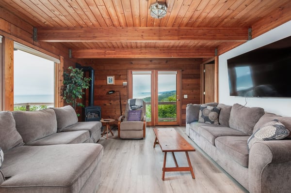 Sink into plush seating and take in sweeping mountain views through floor-to-ceiling windows in this warm, wood-paneled living room designed for your ultimate relaxation.