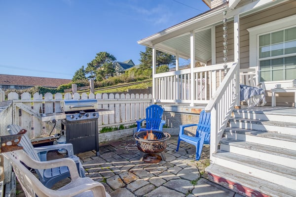 Your private patio features colorful Adirondack chairs around a cozy fire pit, perfect for evening gatherings with BBQ nearby.
