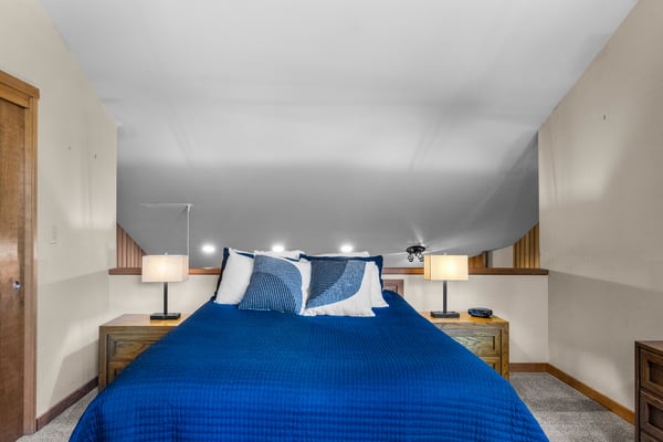 Sink into plush blue linens in your cozy loft bedroom, where warm bedside lighting and thoughtful details create the perfect retreat after a day of adventure.