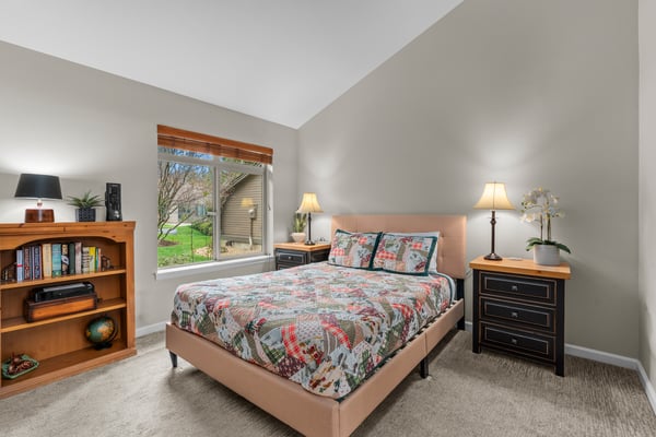 Your cozy bedroom retreat features soft lighting, a plush bed dressed in cheerful linens, and natural light that brings warmth into your restful space.