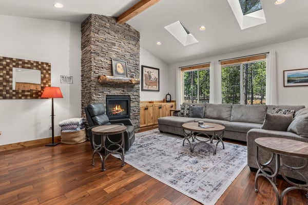 Unwind in your spacious living room with soaring ceilings, cozy stone fireplace, and abundant natural light streaming through skylights and windows.
