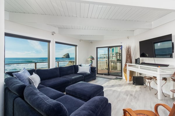 Sink into plush navy sofas while gazing at endless ocean views through floor-to-ceiling windows in your bright, airy living space.