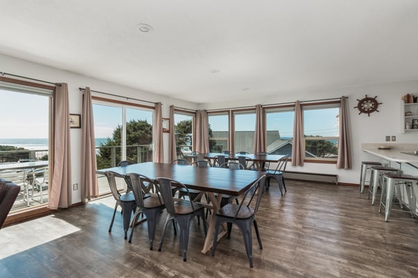 Gather around the large dining table with ocean views streaming through floor-to-ceiling windows—your perfect spot for memorable meals and laughter with loved ones by the sea.