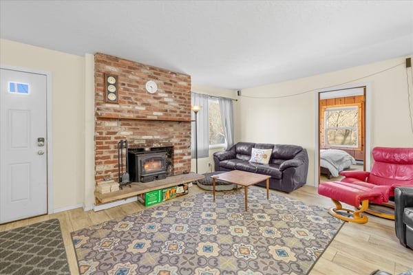 Unwind in your cozy living room with exposed brick fireplace, comfortable leather seating, and warm natural light streaming through windows.