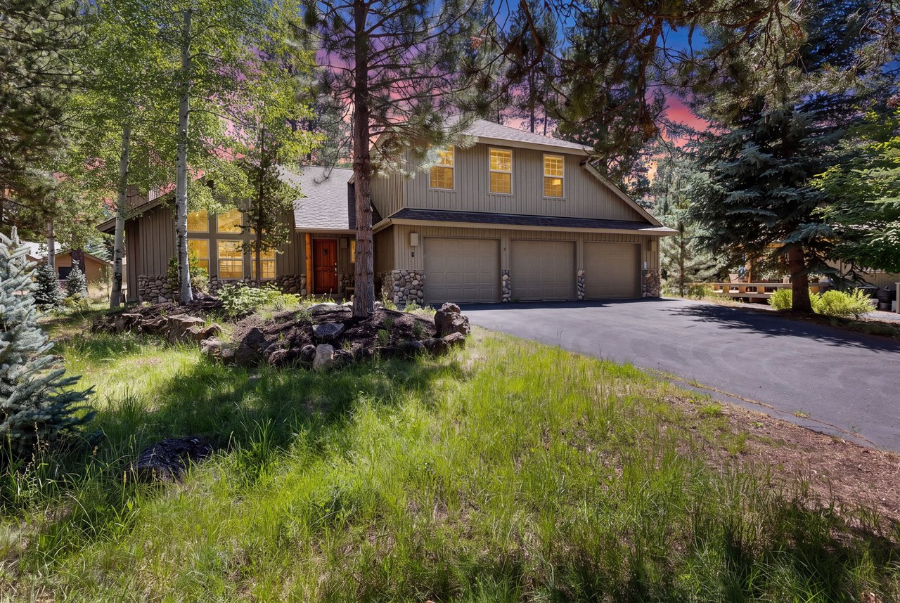 Spacious mountain retreat nestled among towering pines, featuring a three-car garage and surrounded by natural beauty. The property sits on a quiet wooded lot with scenic sunset views.