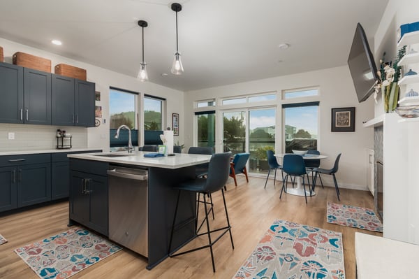 Your gourmet kitchen features sleek navy cabinets, a spacious island for meal prep, and panoramic windows that frame stunning mountain views while you cook.