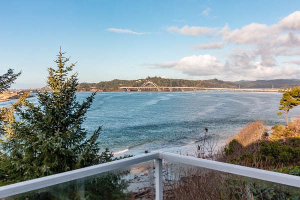 Stunning waterfront view showcases a scenic bridge spanning calm blue waters, framed by lush coastal vegetation and rolling hills.
