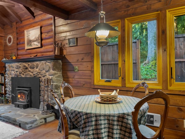 Gather around the rustic dining table where you'll share meals by the crackling stone fireplace in this charming log cabin retreat.