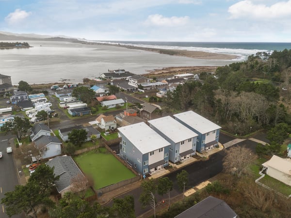 Aerial view of beachside community with modern vacation rentals overlooking pristine coastline and estuary waters.