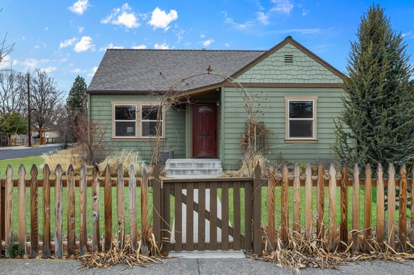Charming green cottage with welcoming red door and white picket fence creates the perfect home-away-from-home retreat.