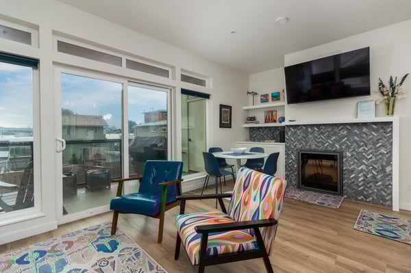 Unwind in your stylish living room featuring a cozy fireplace, vibrant seating, and floor-to-ceiling windows flooding the space with natural light.