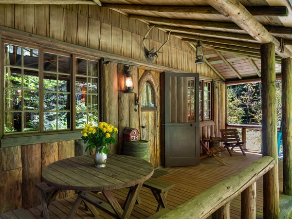 Relax on your private covered porch with rustic wood beams overhead, where fresh flowers await and forest views create your peaceful retreat.