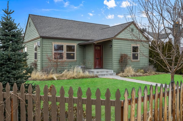 A charming green-sided property surrounded by mature trees and landscaped grounds, creating a peaceful residential setting for your stay.