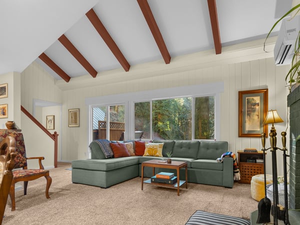 Sink into the plush sectional sofa and admire exposed wooden beams while natural light pours through large windows overlooking lush greenery.