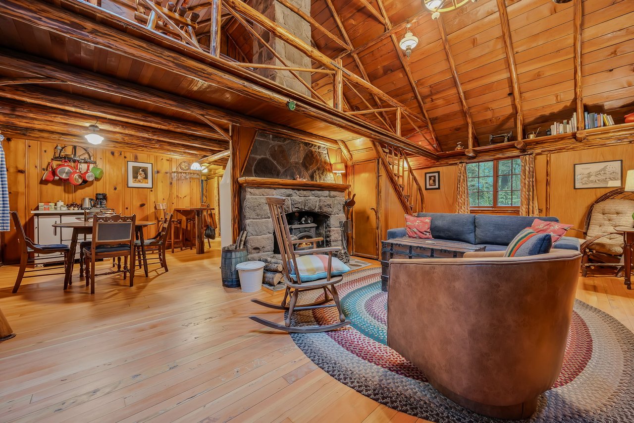 Unwind in your rustic cabin retreat with exposed beams, stone fireplace, and cozy seating that invite peaceful evenings.