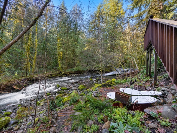 Property nestled alongside a rushing forest stream, surrounded by lush Pacific Northwest woodland and moss-covered rocks.